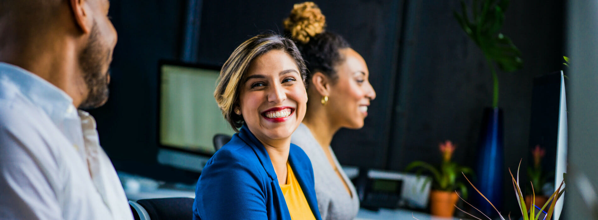 Worker smiling while working next to colleagues at their desk.