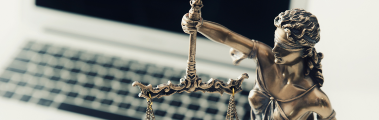 Statue of Lady Justice in front of a laptop.