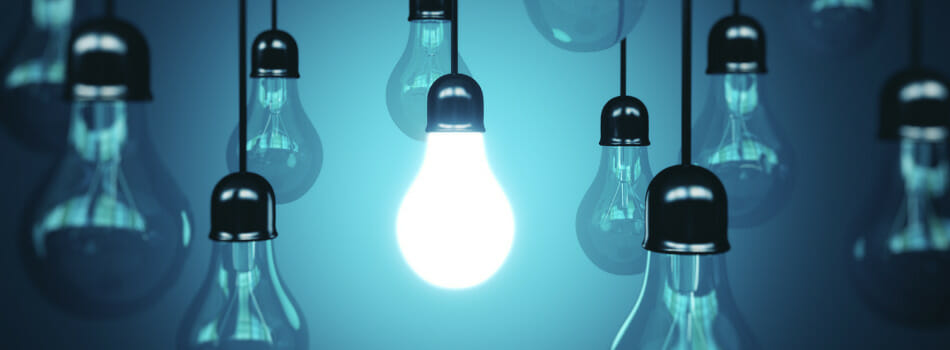Photo illustration of a single lightbulb illuminated in a group of other bulbs.