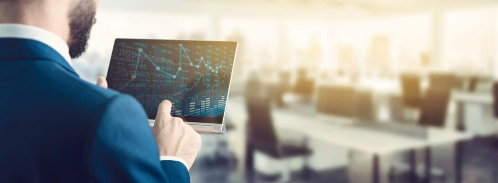 Executive in a suit looking at stats and charts on his tablet.