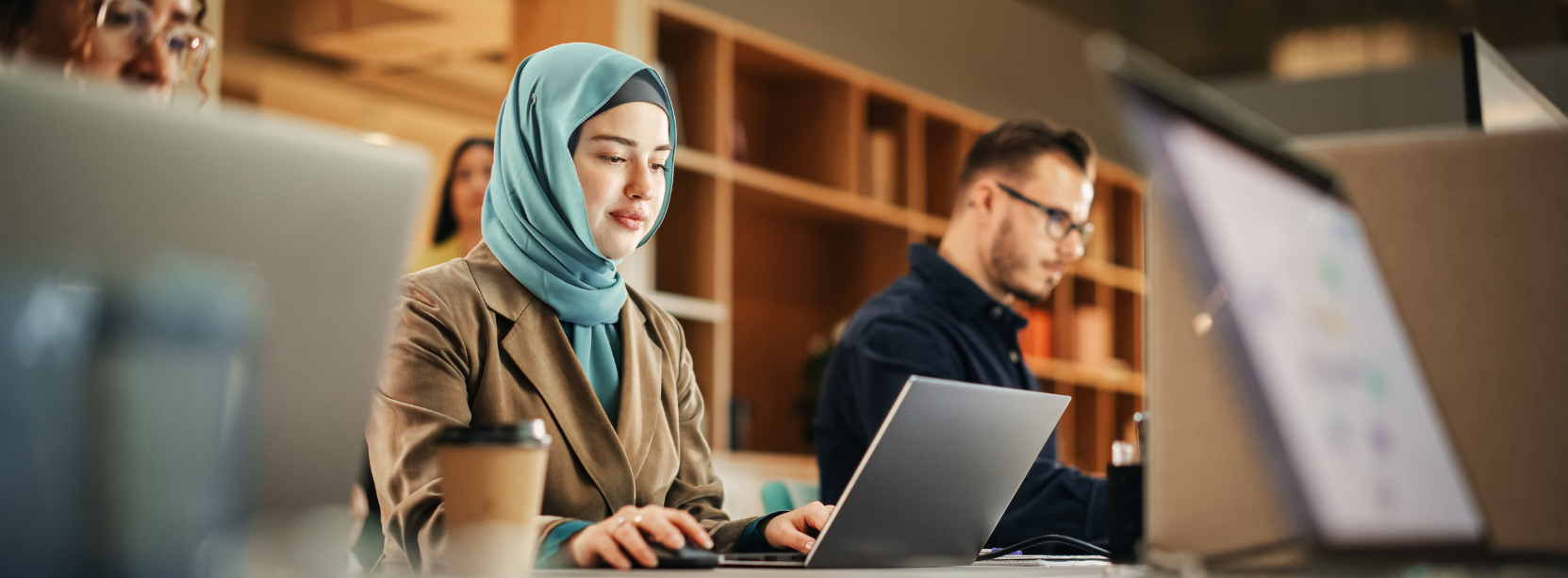 Women sitting in front of her laptop and alongside co-workers.