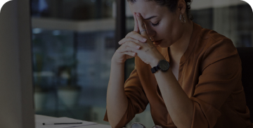 A woman sitting at a desk with her head in her hands