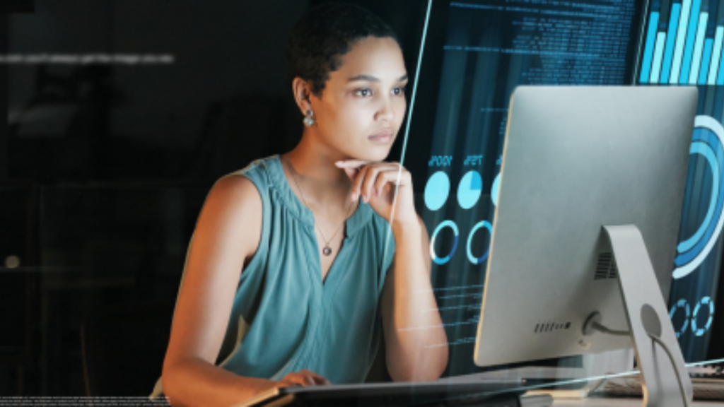 Photo of a woman looking at data on a computer monitor.