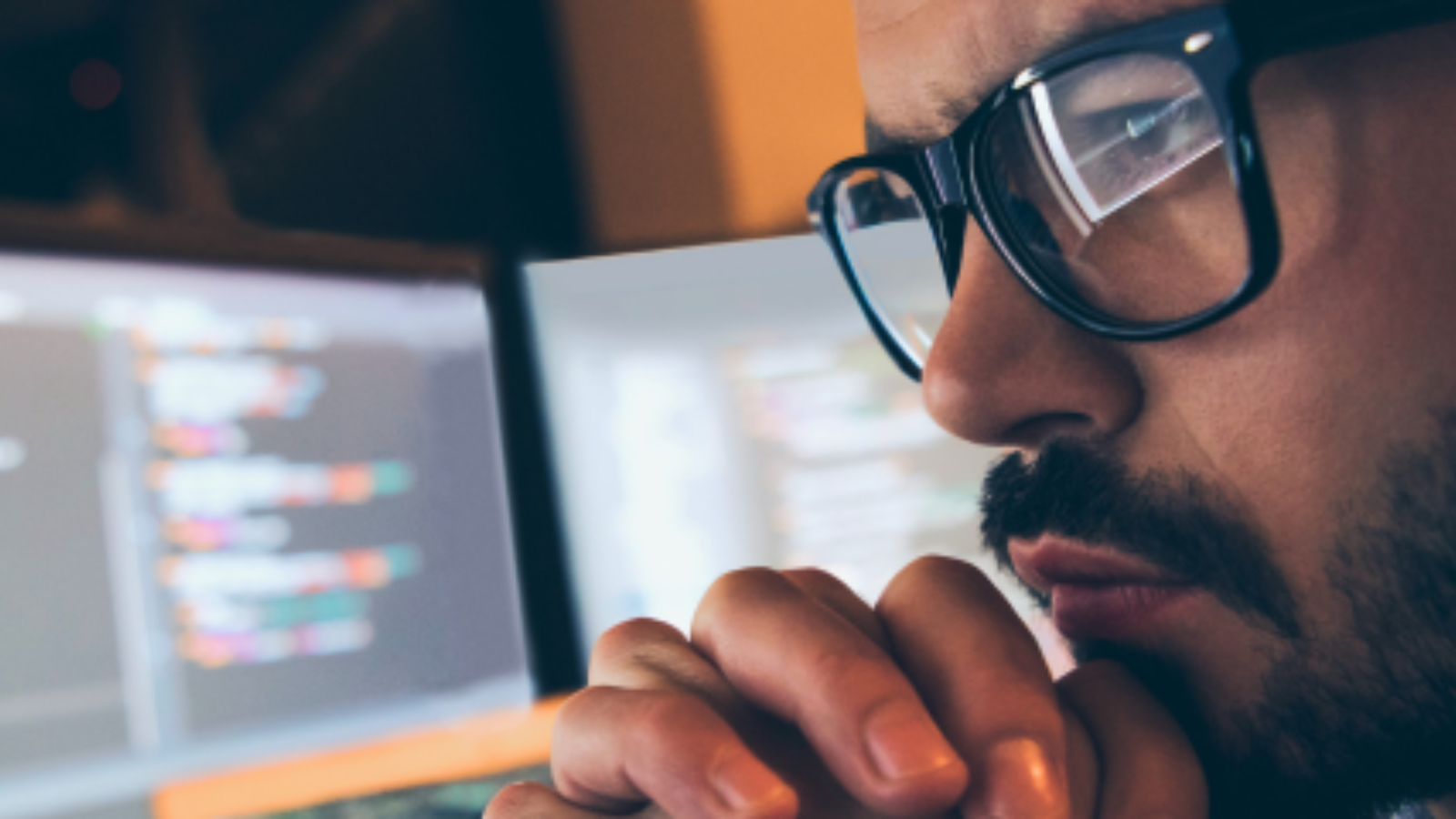 Photo of man looking at computer monitors.