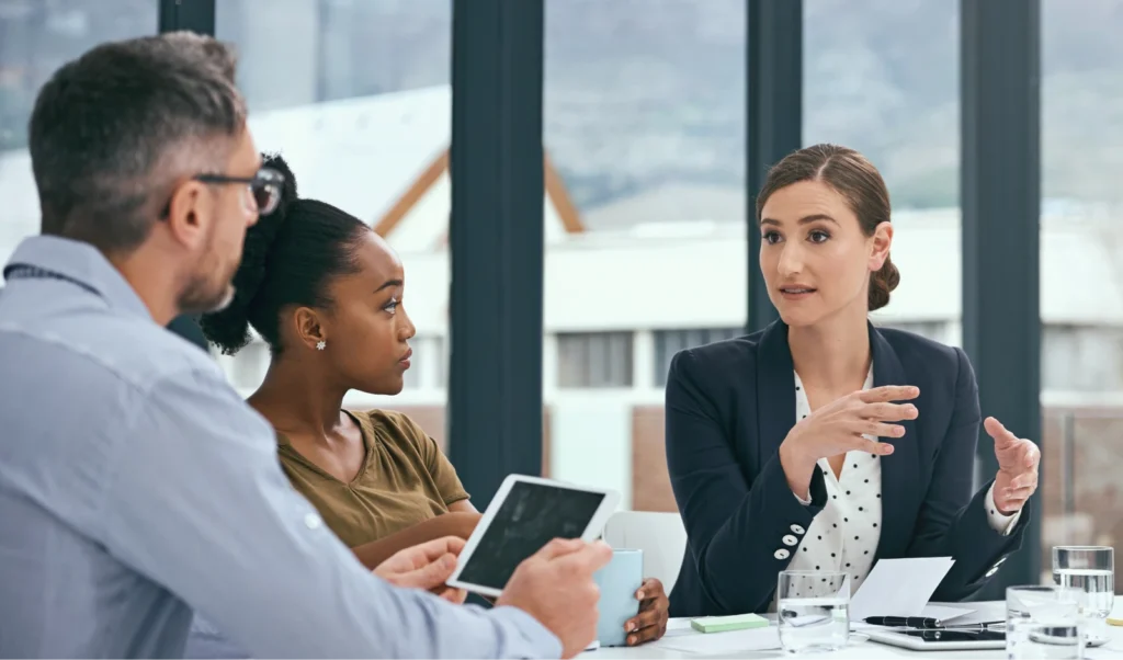 Photo of woman talking to colleagues during a meeting.