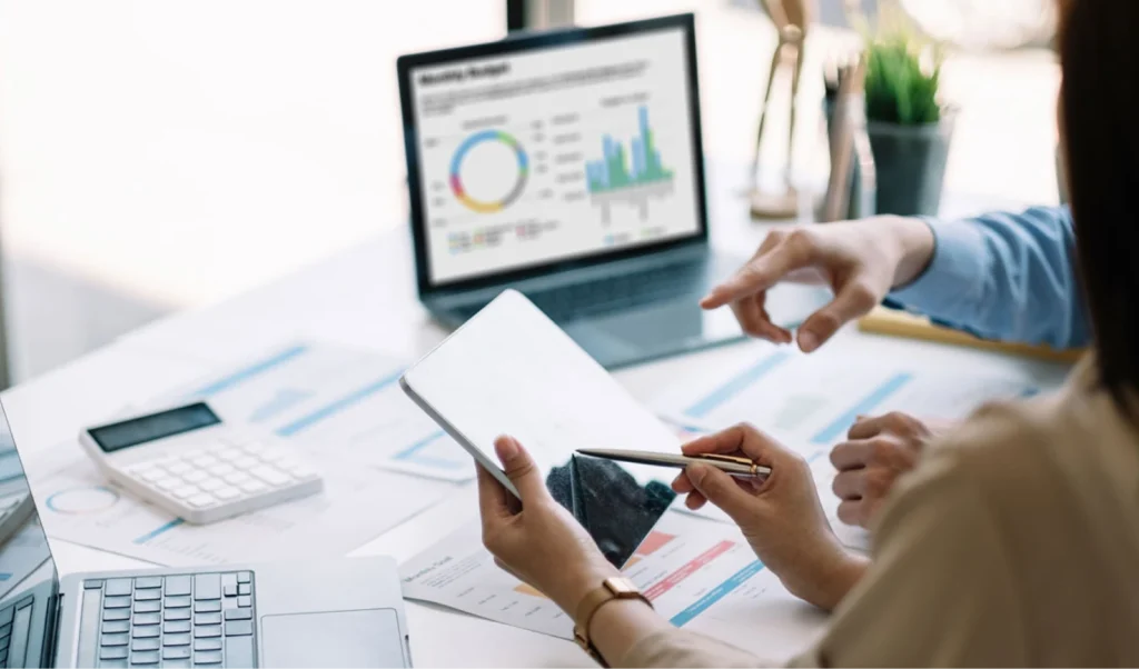 Photo of business professionals looking at data on tablet and laptop.