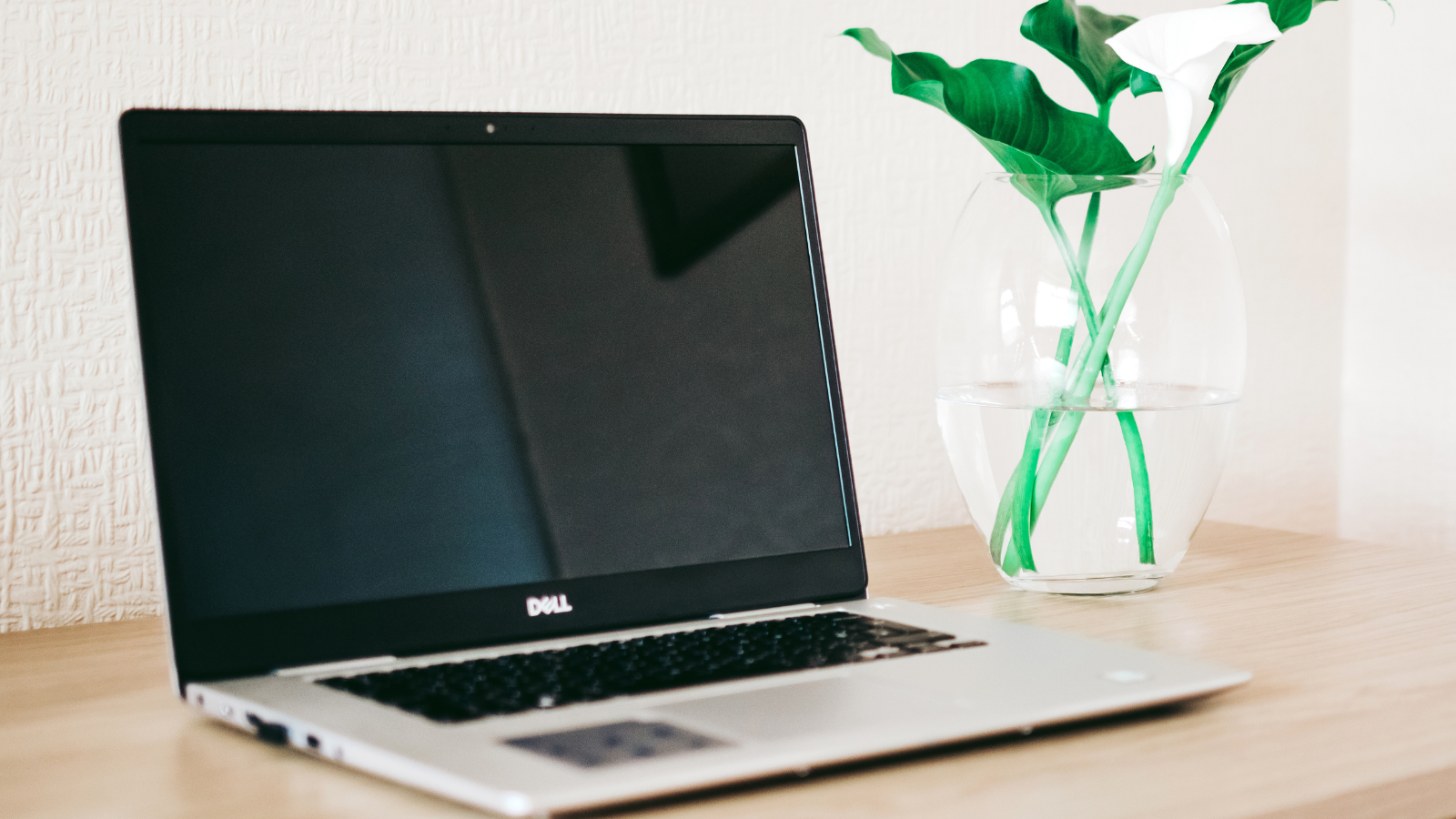 Dell laptop sitting on desk with flowers